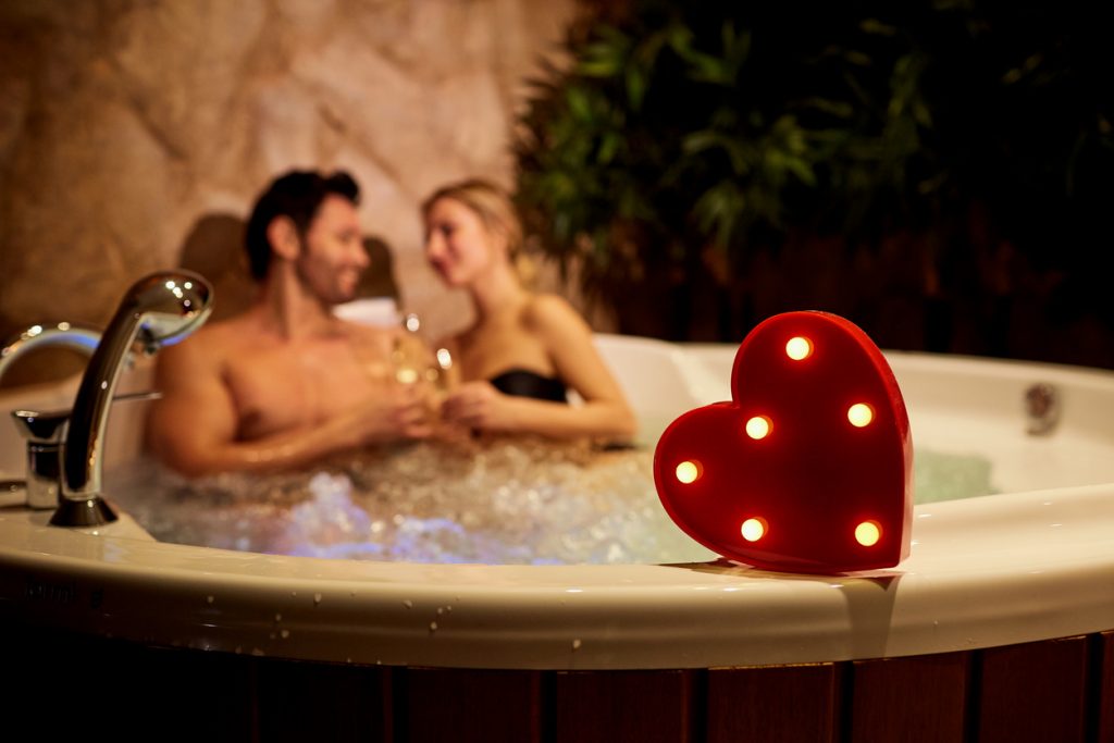 Heart on a background of a romantic couple with champagne in the a hot tub